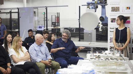Professor Greg Lynn speaking to a group of jurors again a backdrop of the robotics cage