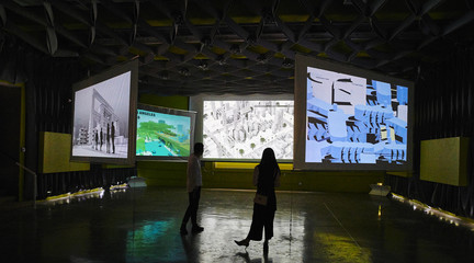Two people standing in front of large screens with projected images