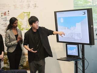 A male student standing in front of a screen presenting work