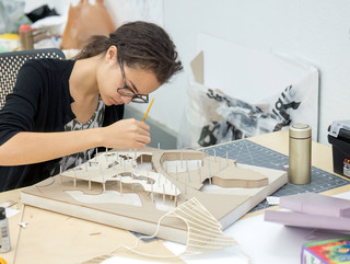 Student leaning over a desk working on a project