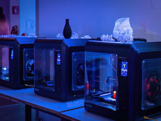 A colorful photo of 3D printers with blue and purple lighting