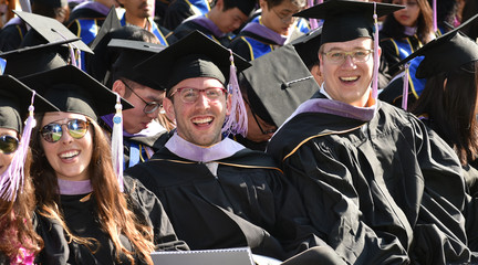 Image of three smiling students in graduation regalia