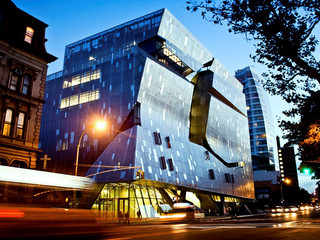 Exterior shot of the Cooper Union Building at 41 Cooper Square in New York. The façade is made up of a stainless steel curtain wall that wraps the entire building.