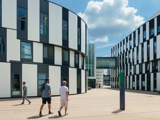 Image of students walking through Campus Wu, a cluster of curved black and white panelled buildings.