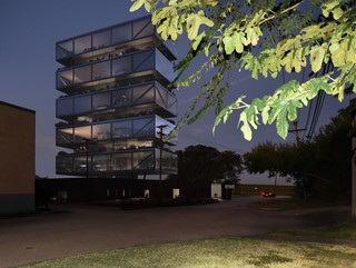 A photo of a glass tower with dark clouds in the background