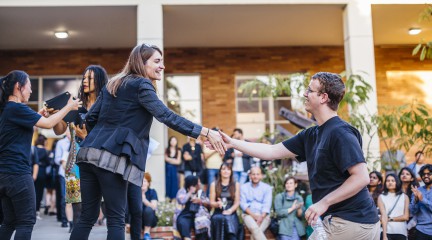 Chair Heather Roberge shaking hands with a male student to congratulate him