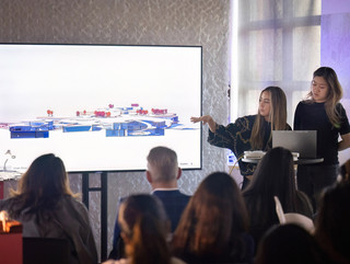 A woman with a VR headset in front of a screen projecting an immersive experience