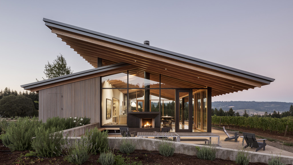 Image of a winery with a sloped wooden roof and glass floor-to-ceiling windows