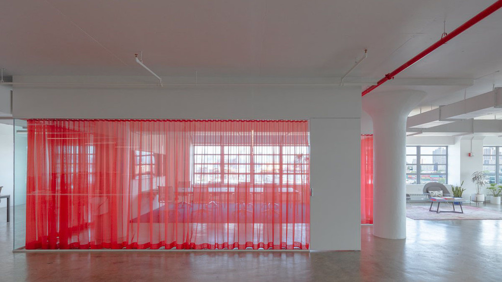 Image of a modern office space with a red curtain dividing the space