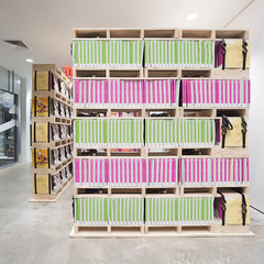 Image of a colorful bookshelf inside a room with concrete floors