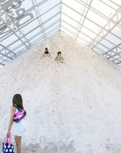 Image of two children sliding down a sand bank inside a structure