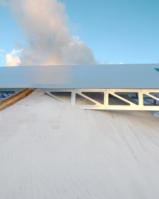 Image of a sand pile rising up to almost cover a structure