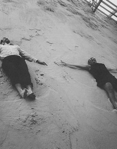Image of two people lying on a sand bank