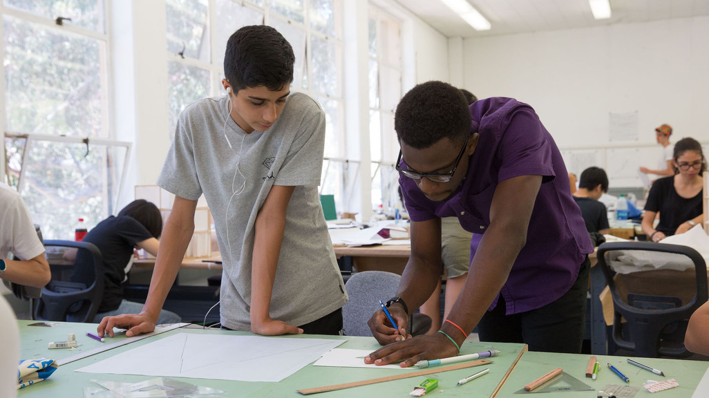 an architecture instructor drawing on an illustration with a pencil while a student watches on