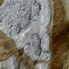 Aerial photograph of dried lake bed with blue pigmentation and a thick streak of brown pigmentation on the right side of the bed.