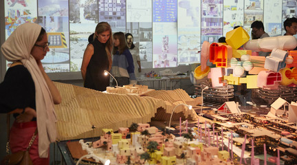 Image of two women looking at the mega-model of structures on the reimagined island of Tuvalu as part of RUMBLE, the end-of-year student exhibition.