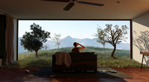 Video still showing a person sitting on a couch in front of a landscape